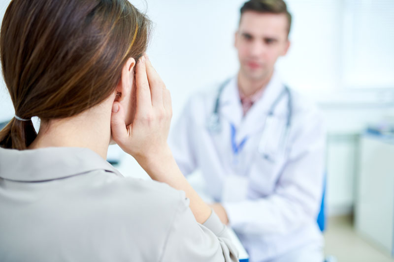 Female patient suffers from earache while consulting with male doctor