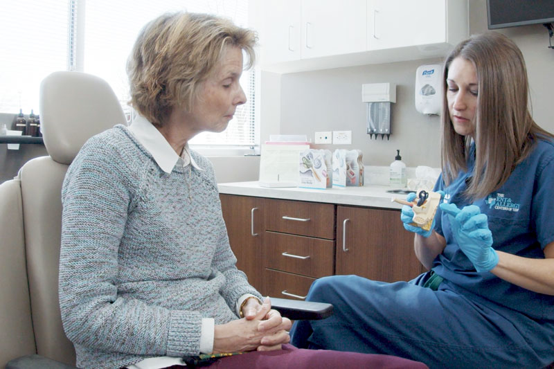 Female doctor discusses ear anatomy and cochlear implant procedure in a medical office with an older female patient