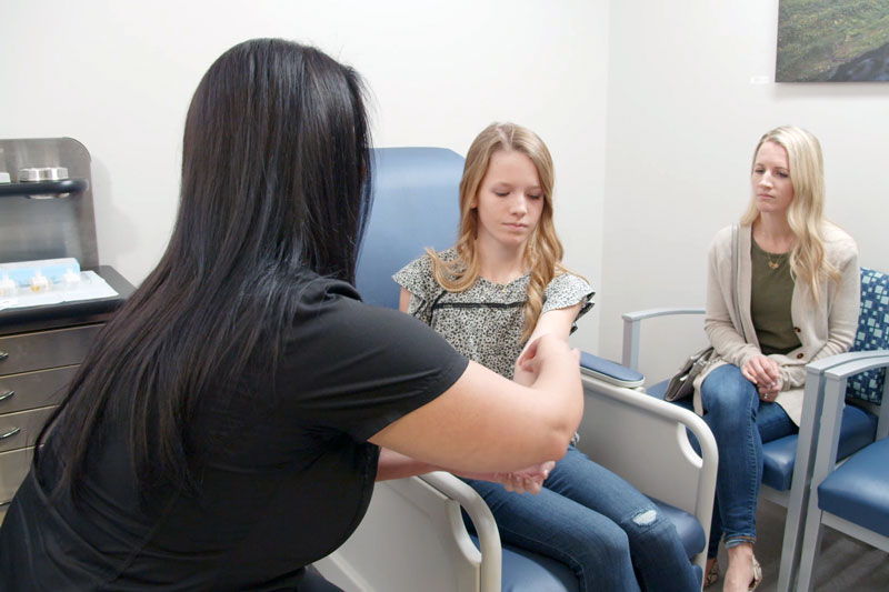 Medical team member conducts allergy test on forearm of young female patient