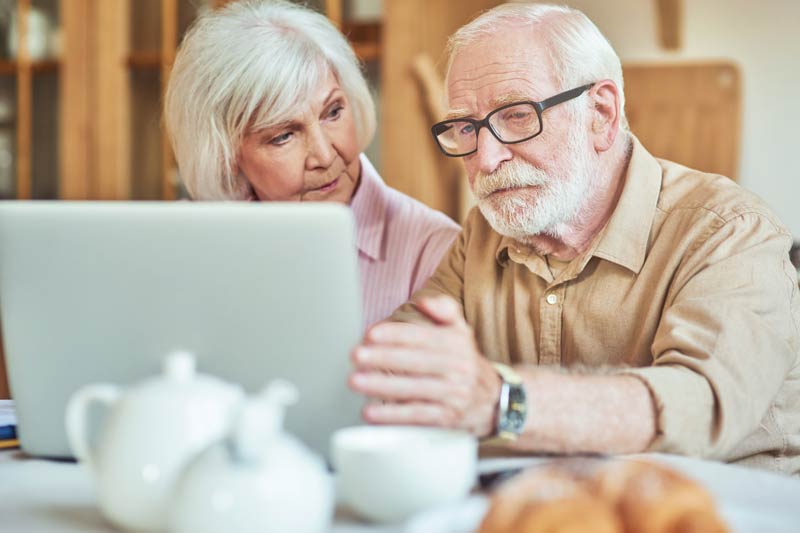 Elderly man in glasses looking at computer