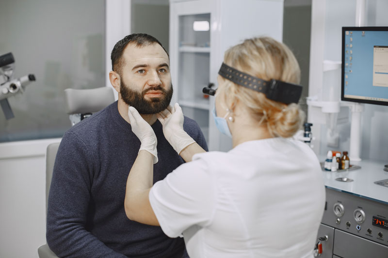 Female physician examining the neck of a male patient