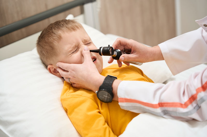 Female physician uses scope to examine young boy’s nose