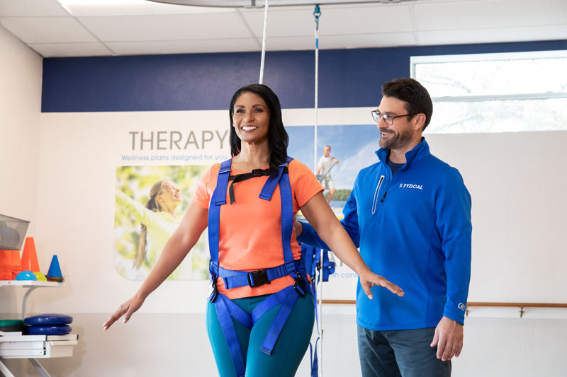 A female patient with difficulties maintaining balance receives assistance from a physical therapist.
