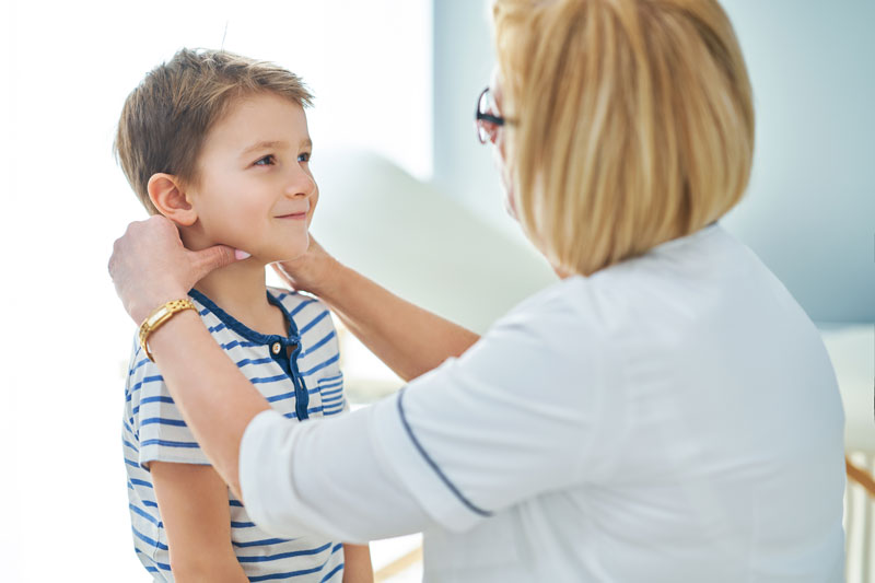Female physician examining young boy’s neck