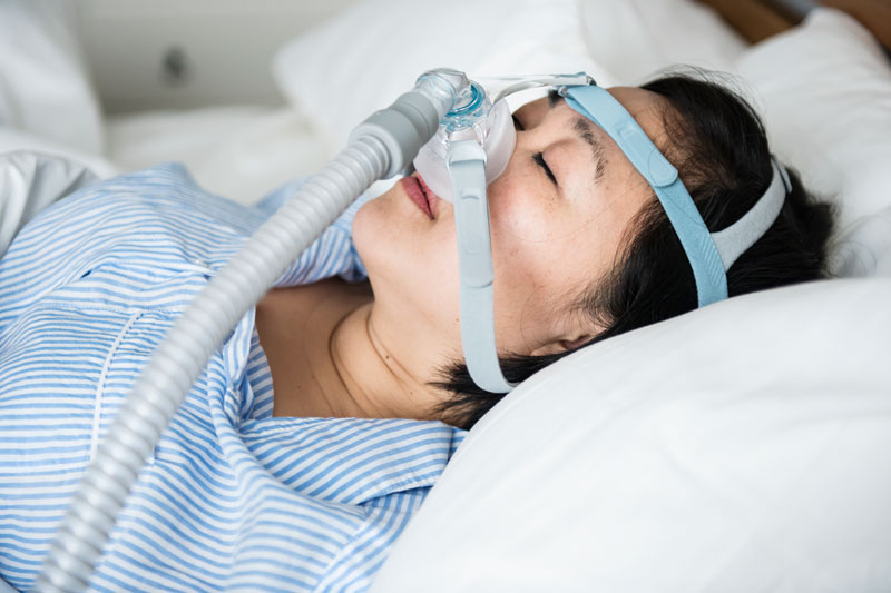 Woman sleeping while wearing a CPAP device