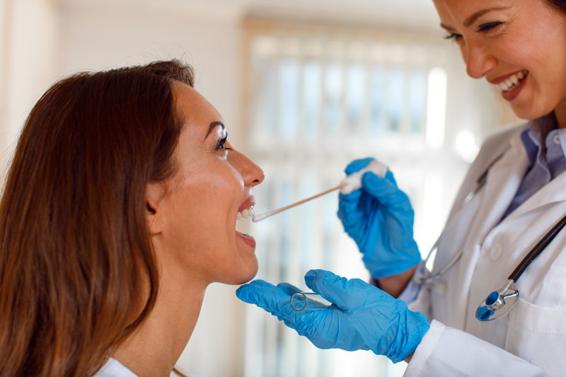 Female doctor examines female patient’s throat