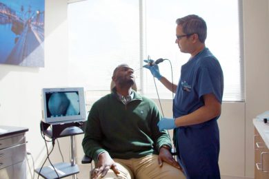 Physician uses scope to view the nasal cavity and sinuses of a male patient in a clinical office.